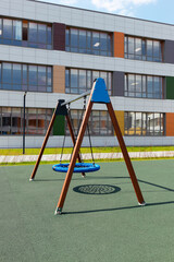 Fototapeta premium Outdoor swing with wicker round seat on green artificial ground. School playground