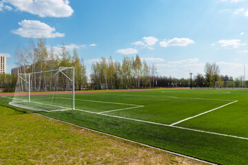 Fototapeta premium School football, soccer field with artificial turf and goals against a blue sky