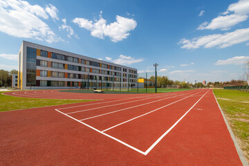 In the school yard: an red artificial turf running track and a soccer field with football goals