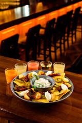 Snacks corn nachos with sun-dried tomatoes, jalapeno peppers, cheese, cream cheese, sauce and strong alcohol in shot glasses on the bar counter of the restaurant.