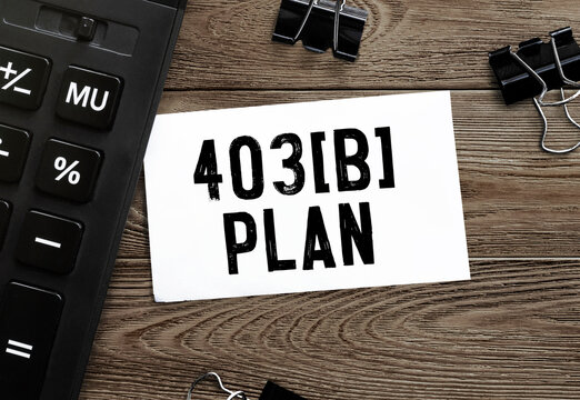 White paper with text 403b plan on a wooden surface with stationery