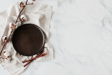 Wooden Plate mockup, linen napkins and cotton flowers top view on marble background. Eco friendly...