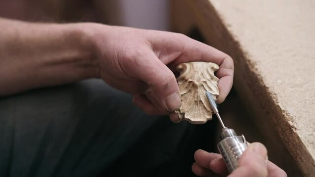Hand carved wood. A carpenter manually carves an ornament on a piece of wood. Close up of hands.