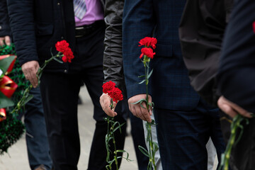 Red carnations in his hands. Memory. Laying flowers at the monument. A sad ceremony.