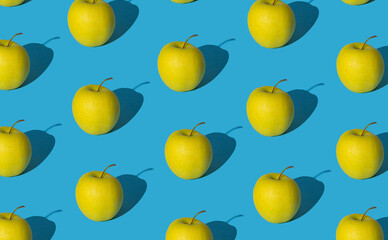 Trendy fruit pattern made of yellow apples on light pastel blue background. Minimal layout. Nature summer concept.