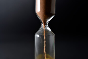 Glass hourglass on a black background. Multicolored glass hourglass.