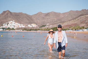 Senior woman surprising her partner while walking distractedly on the beach. Concept: happiness,...