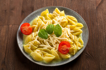 Pasta in cream sauce with cheese garnished with spinach and cherry tomatoes on a wooden table.