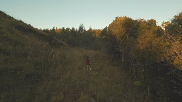 Aerial cinematic stabilized shot of a woman walking in a mountain forest at sunset. City of Canela in the state of Rio Grande do Sul, Brazil.