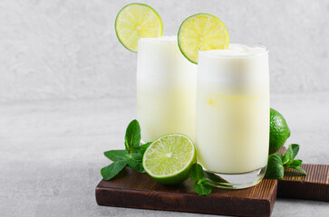 Brazilian Lemonade, Refreshing Creamy Lemonade or Limeade with Lime Slices and Mint on Grey Background