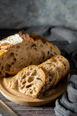 Sourdough homemade bread cut into slices on cutting board, dark moody food photo.