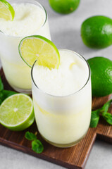Obraz na płótnie Canvas Brazilian Lemonade, Refreshing Creamy Lemonade or Limeade with Lime Slices and Mint on Grey Background