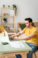 Male accountant sitting at desk at home.