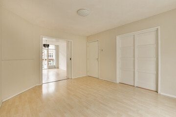 an empty living room with wood floors and white doors leading to the front door that leads into the dining area