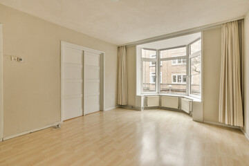 an empty living room with wood flooring and large windows looking out onto the street in front of the house