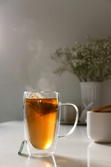 black tea in a las cup on white table, flower in background 