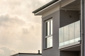 Modernes Wohnhaus mit großen Fenstern und Balkon mit Glasgeländer
