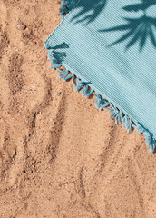 Bright summer beach vacation concept background with tropical leaves shadows and towel on sand. Copy space