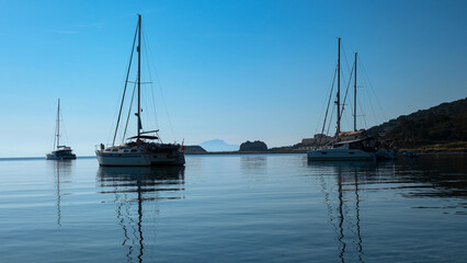 Fototapeta na wymiar Early morning on calm sea, blue sky and sailing yacht, calmness, serenity and meditation