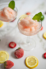Sorbete de fresa en copa decorada con fresas y rebanadas de lima en fondo de mármol
