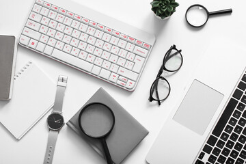 Composition with glasses, magnifiers, laptop and keyboard on white background
