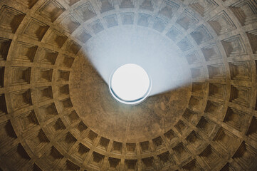 Fototapety  Wnętrze Panteonu w Rzymie z widokiem na imponujący sufit z otworem oculus, przez który wpada światło słoneczne. Ten unikalny widok ukazuje majestatyczną konstrukcję i niesamowite efekty świetlne.