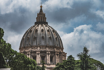 Imponująca kopuła Bazyliki Świętego Piotra w Rzymie, widziana z perspektywy Muzeum Watykańskiego. Masywne i majestatyczne struktury są symbolem historycznej i religijnej potęgi Watykanu. - obrazy, fototapety, plakaty