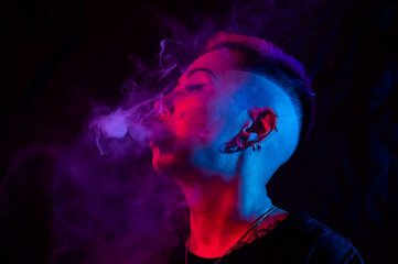 Profile Asian woman with short haircut smoking in neon light.