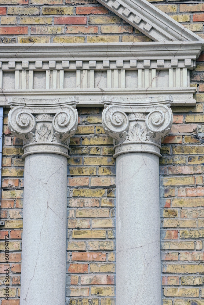 Wall mural two white concrete columns with cracks on a brown brick wall in the street