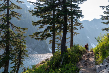Distant people taking in breathtaking view of an alpine lake from hiking trail.