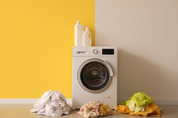 Stacks of dirty clothes and washing machine with detergent in laundry room