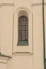 one old window behind a black iron grate on a white stone wall of a building on the street