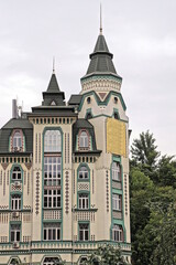 a large tall gray house with a tower under a green tiled roof against the sky