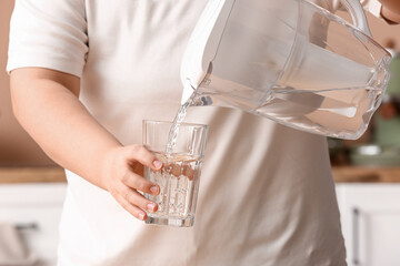 Woman pouring water from filter jug into glass