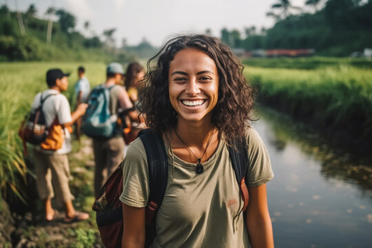 young adult woman traveling, hiking along a small river in tropical nature with other tourists or friends and local people, fictional place