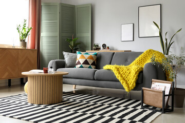 Interior of stylish living room with cozy grey sofa and reed diffuser on coffee table