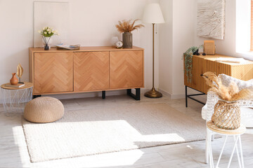 Interior of bright living room with cozy armchair and wooden cabinets