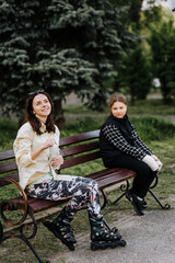 A young woman in roller skates and a sad girl, a child in a cast, bandages with broken arms, looks,...