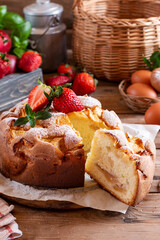 Sponge cake with apples and strawberries on a board on a wooden table. Homemade pie