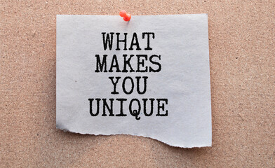 The question What Makes You Unique typed on a piece of lined paper and pinned to a blue notice board