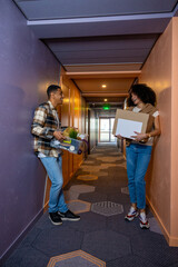 Young couple carrying their clothes in the hotel corridor