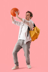Male student with ball on pink background