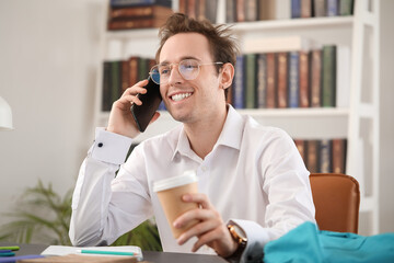Male student talking by phone while doing lessons at home