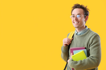 Male student with notebooks on yellow background