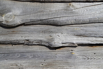 A heavily cracked wooden wall made of old and crooked panels with multiple knots as a background