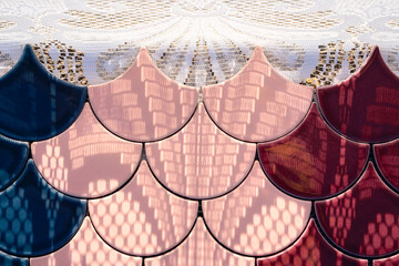 Multicolored raindrop shaped ceramic mosaic tile against white lace