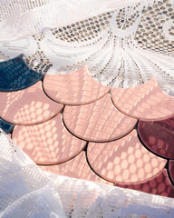 Multicolored raindrop shaped ceramic mosaic tile against white lace