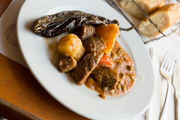 Juicy beef stew in gravy served with with marinated pepper on plate