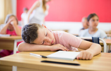 Tired little boy lying on work desk put head on his hand, feel exhausted with hard learning process