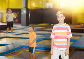 Portrait of smiling preteen boy spending time in modern inflatable amusement park, posing in...
